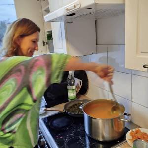 Osoba miesza krem dyniowy chochlą w dużym garnku na kuchence