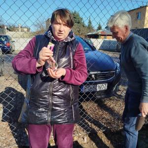 Uczestniczka ŚDS przesypuje nasionka z saszetki na dłoń, stojąc nad skrzynia do sadzenia roślin