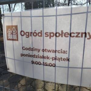 Tabliczka wisząca na ogrodzeniu Ogrodu Społecznego informuje że ogród otwarty jest dla wszystkich od poniedziałku do piątku w godzinach 9:00 - 15:00