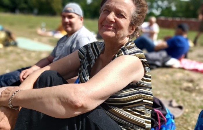 Starsza kobieta siedzi na plaży i pozuje do zdjęcia