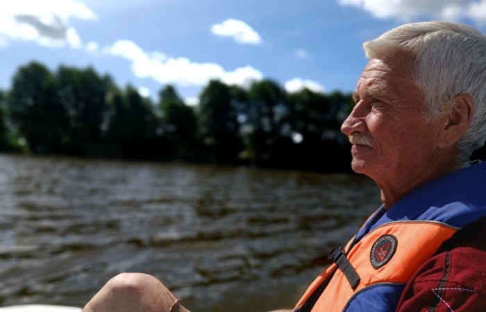  Starszy mężczyzna płynie rowerem wodnym po jeziorze i wpatruje się w dal