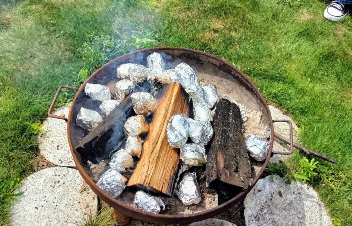 Ziemniaki w sreberkach pieką się przy ognisku 